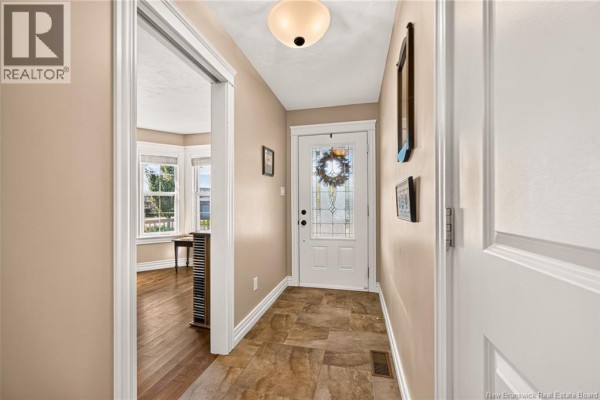 Interior entryway with tan walls, beige tile floor, and a view into a living room with bay windows. - 51 Thornhill Crescent, Moncton