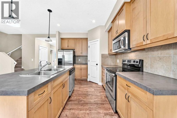 Kitchen view with stainless steel appliances, light wood cabinets, and stone backsplash. - 510, 413 River Avenue, Cochrane