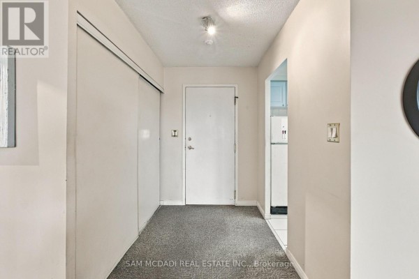 Apartment entryway with a white door, white closet doors, and grey carpet. - 510 - 135 Hillcrest Avenue, Mississauga