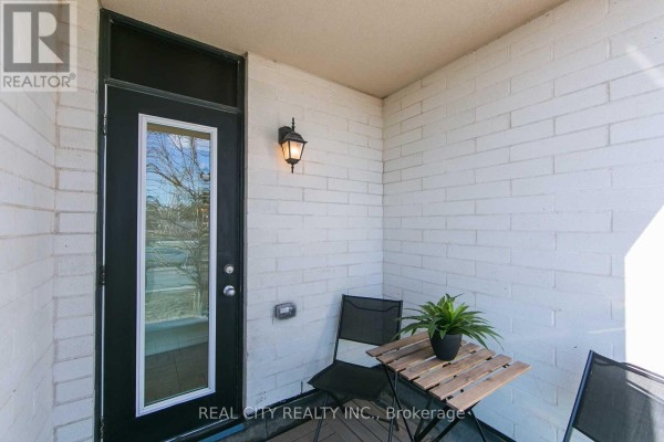 A small balcony with a wooden table, two chairs, and a potted plant. - 510 - 142 Widdicombe Hill Boulevard, Toronto