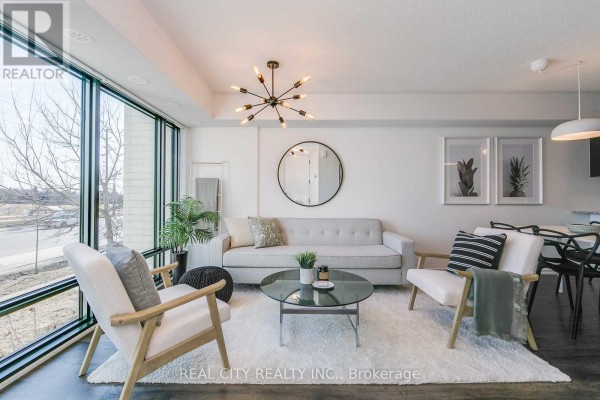 Living room with large windows, light gray sofa, two armchairs, and a glass coffee table. - 510 - 142 Widdicombe Hill Boulevard, Toronto