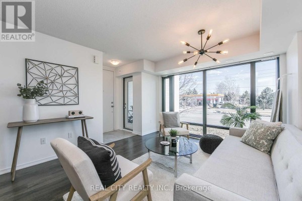 Living room with large corner windows, white walls, and dark hardwood floors. - 510 - 142 Widdicombe Hill Boulevard, Toronto
