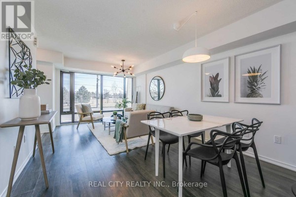 Dining area with a white table and black chairs next to the living room. - 510 - 142 Widdicombe Hill Boulevard, Toronto