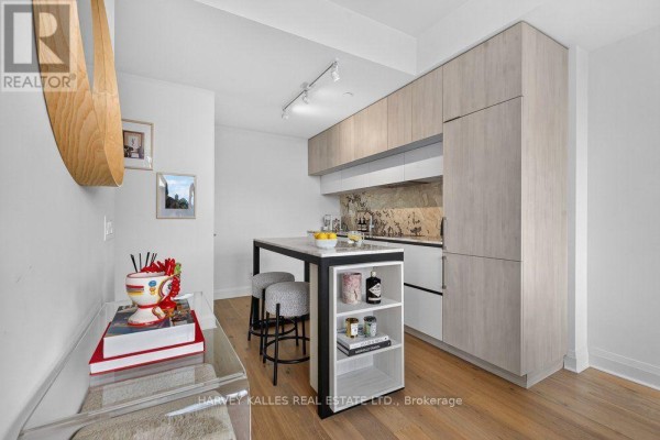 Kitchen and dining area with light wood cabinets, marble island, and dining table. - 510 - 151 Avenue Road, Toronto