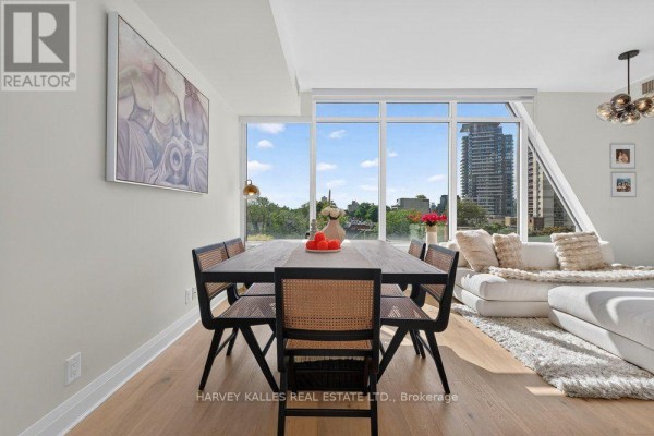 Dining area with wood table, cane-back chairs, and view of city buildings. - 510 - 151 Avenue Road, Toronto