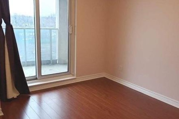Bedroom with hardwood floors, beige walls, and a sliding glass door with dark curtains. - 510 - 3 Rean Drive, Toronto