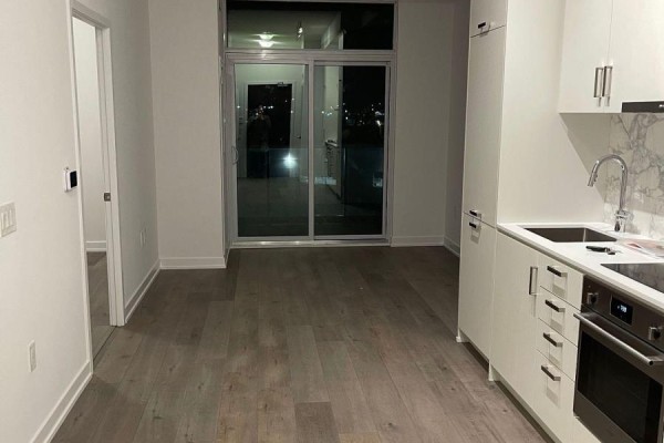 View of the living area and kitchen with a sliding glass door to a balcony. - 510 - 60 Honeycrisp Crescent, Vaughan