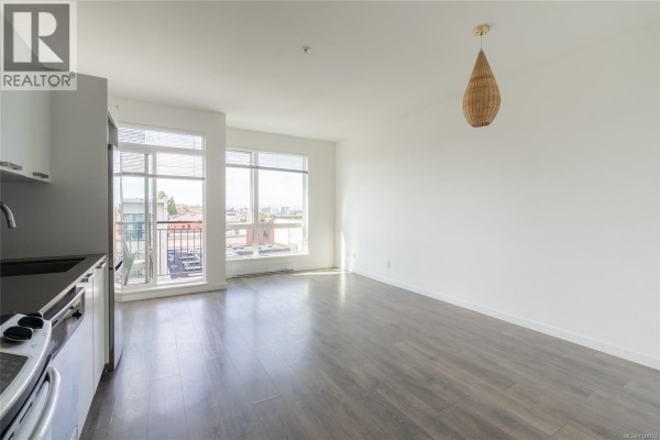 Open concept living area with large windows and city views, overlooking the kitchen area. - 510 517 Fisgard St, Victoria