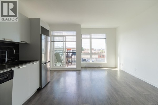 View of the living area and kitchen from the side, showing access to a balcony. - 510 517 Fisgard St, Victoria