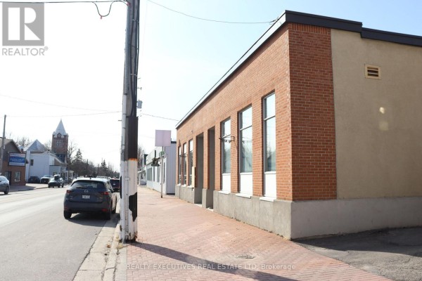 Side view of the brick building with large windows and paved sidewalk. - 510 Main Street, North Dundas