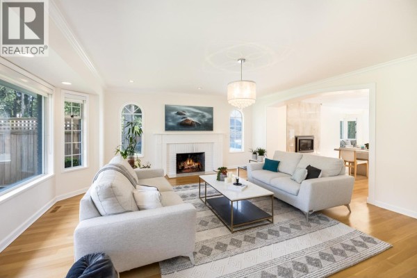 Living room with light-colored sofas, a fireplace, and arched windows. - 510 Newdale Place, West Vancouver