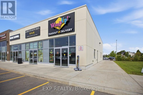 Exterior of a commercial building with multiple storefronts and a cloudy sky. - 5100 Kanata Avenue, Ottawa