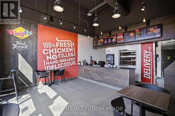 Interior view of a restaurant counter with menus, seating, and a large red graphic. - 5100 Kanata Avenue, Ottawa