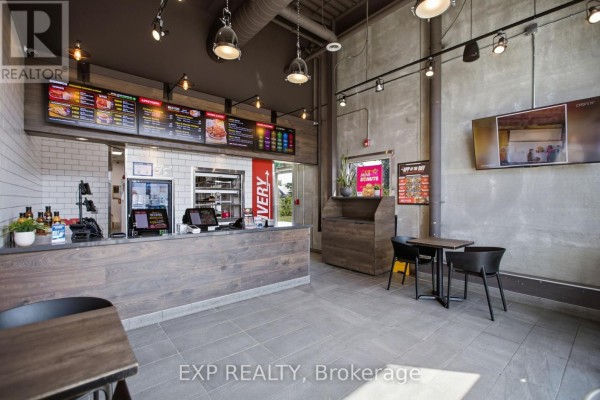 Restaurant interior with a wooden counter, tiled floor, and a digital menu board. - 5100 Kanata Avenue, Ottawa