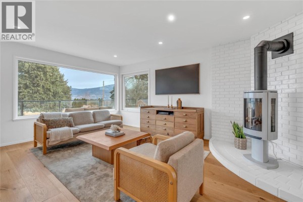Bright bedroom with wooden furniture, large window, and closet access. - 5100 Wilson Road, Summerland