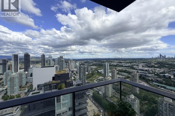 Balcony view of city buildings and mountains under a cloudy sky. - 5101 2108 Gilmore Avenue, Burnaby