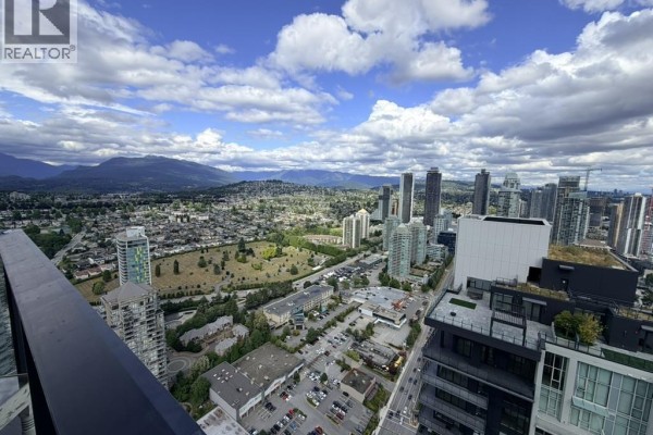 City and mountain view from a high-rise apartment with buildings below. - 5101 2108 Gilmore Avenue, Burnaby