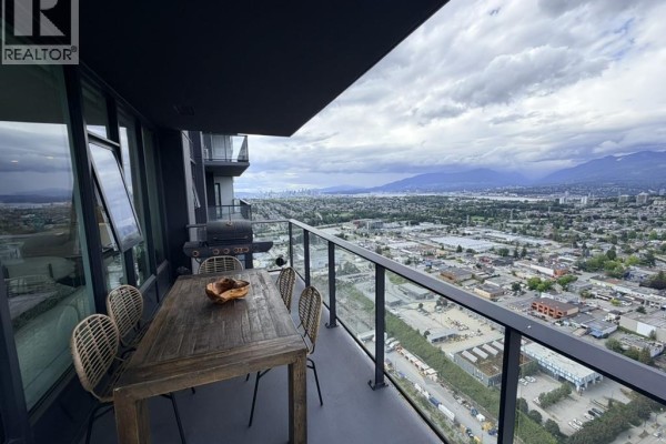 Balcony with dining set and barbecue overlooks city and mountain landscape. - 5101 2108 Gilmore Avenue, Burnaby