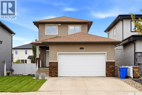 Wooden stairs with white railings lead up to a back door beside a beige vinyl-sided wall. - 5101 Tutor Way, Regina