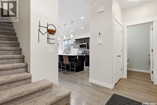 A kitchen with dark wood cabinets, stainless steel appliances, a white countertop, and gray tiled backsplash. - 5101 Tutor Way, Regina