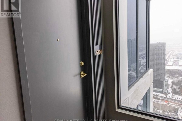 Apartment entrance door numbered 5102 with gold knob, adjacent to large windows overlooking the city. - 5102 - 5 Buttermill Avenue, Vaughan