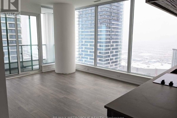 Living area with large windows offering a city view, light wood floors, and a central white column. - 5102 - 5 Buttermill Avenue, Vaughan