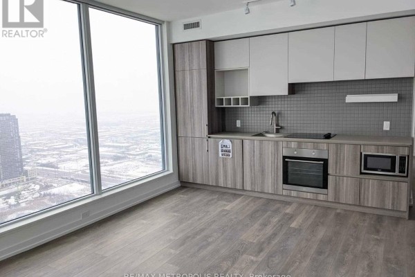 Contemporary kitchen with dual-tone cabinets, integrated appliances, and large windows with city views. - 5102 - 5 Buttermill Avenue, Vaughan