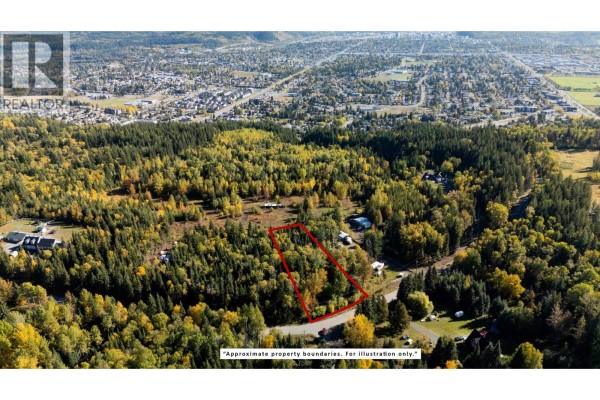 Wide aerial view of a forested property lot outlined in red near a residential area. - 5102 Cranbrook Hill Road, Prince George