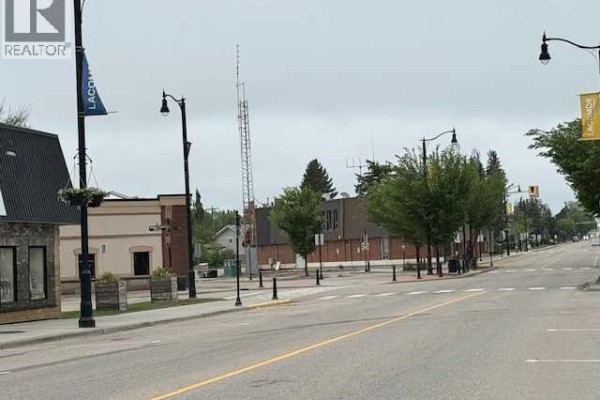 Street view of 50 Avenue, Lacombe, with various storefronts and lampposts. - 5105 50 Avenue, Lacombe