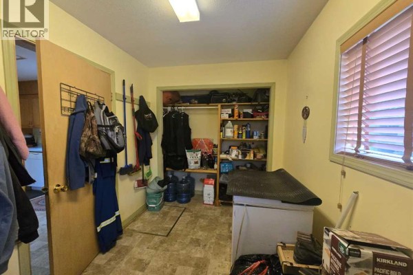 Storage room with shelving, various items, coats hanging on the wall, and a refrigerator. - 5106 Center Avenue, Robb