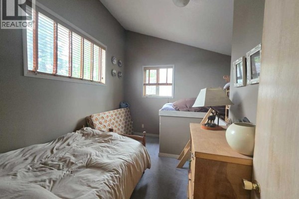 Bedroom with two beds, wood furniture, and windows with blinds. - 5106 Center Avenue, Robb