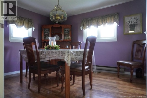 Dining room with a wooden table, chairs, china cabinet, and purple walls with lace curtains. - 5106 Route 495, Sainte Marie De Kent
