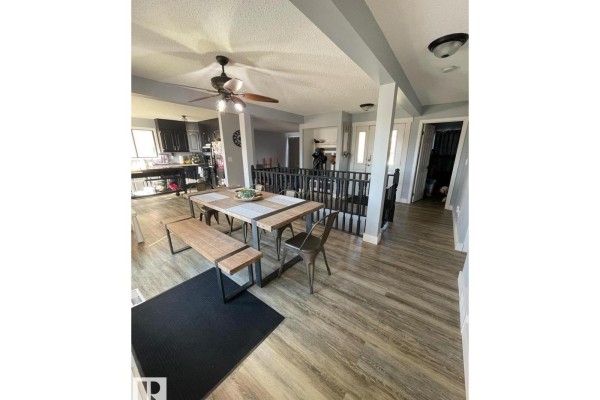Open concept dining area and kitchen with light wood flooring and black cabinetry. - 5105 58 Av, Elk Point