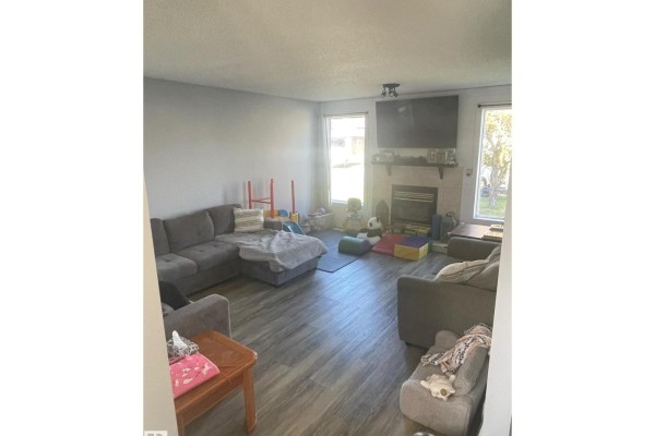 Living room with a large sectional sofa, a fireplace, and two windows with natural light. - 5105 58 Av, Elk Point