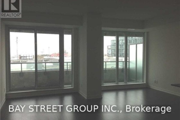 Living area with white walls, dark hardwood floors, and a large sliding glass door. - 511 - 150 East Liberty Street, Toronto