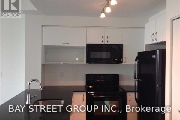 Kitchen with white cabinets, black countertops, a black refrigerator, and a microwave. - 511 - 150 East Liberty Street, Toronto
