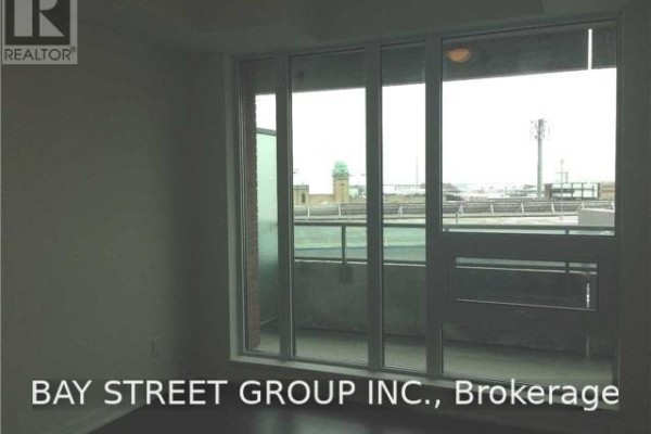 View from a sliding glass door showing a balcony and urban buildings in the distance. - 511 - 150 East Liberty Street, Toronto