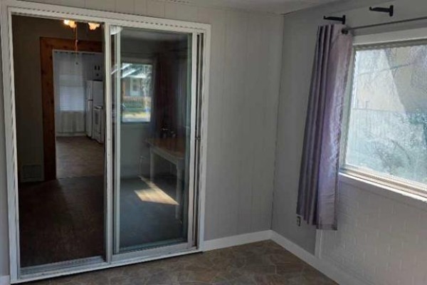 Interior view of a room with beige wood paneling, large sliding glass doors, and a window with grey curtains. - 511 12c Street N, Lethbridge