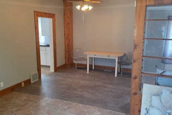 View of a dining area with light wood trim, beige walls, a table with two chairs, and a doorway to the kitchen. - 511 12c Street N, Lethbridge