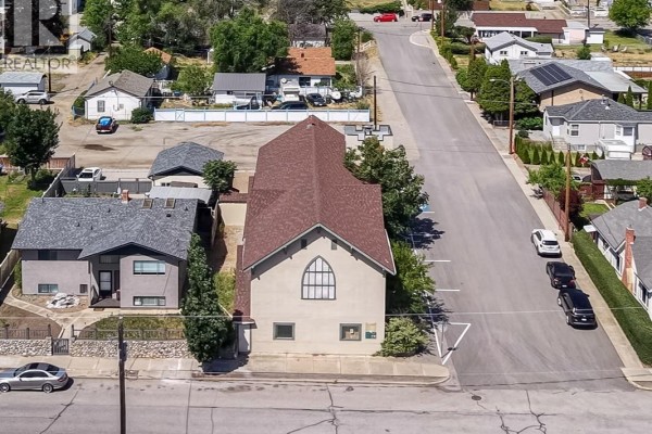 Side aerial view of the beige commercial building with a distinct arched window and adjacent residential property. - 511 Church Avenue, Oliver