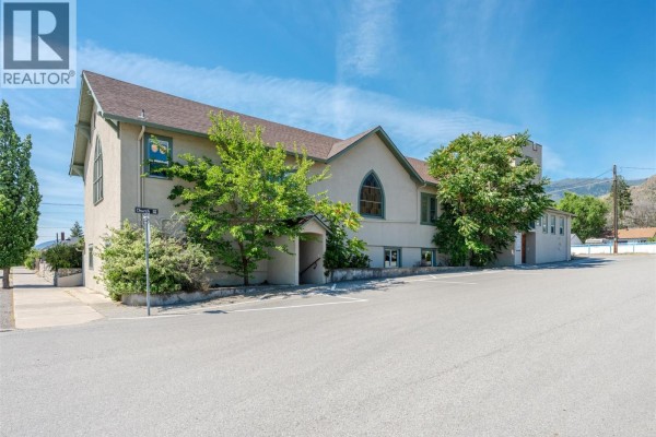 Exterior view of the beige commercial building with a brown roof, arched windows, and surrounding trees. - 511 Church Avenue, Oliver