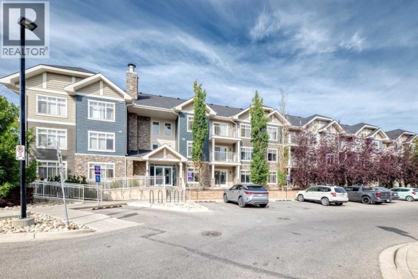 Side exterior view of the apartment building with multiple floors, balconies, and surrounding trees. - 5114, 155 Skyview Ranch Way Ne, Calgary