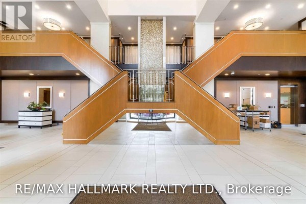 A building lobby with a central split staircase and wood paneling. - 512 - 100 Harrison Garden Boulevard, Toronto