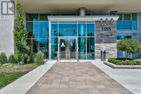 The modern glass entrance to the 1055 Southdown Road condominium building with paved walkway. - 512 - 1055 Southdown Road, Mississauga