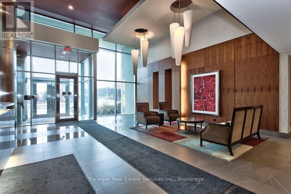 The building lobby features a wood-paneled wall, contemporary seating, and large windows. - 512 - 1055 Southdown Road, Mississauga