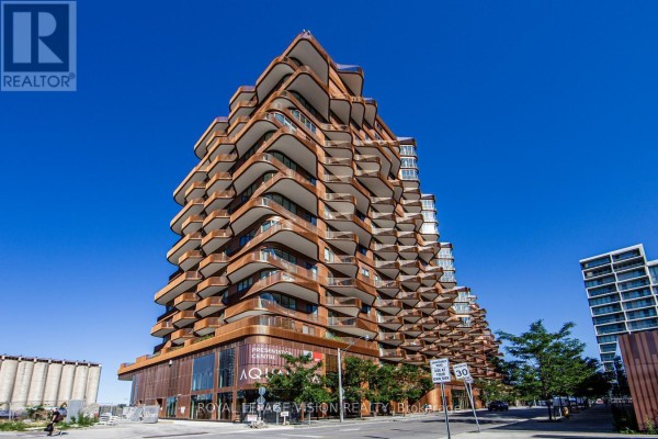 Exterior of a modern apartment building with a unique wavy, copper-colored facade and balconies. - 512 - 155 Merchants' Wharf, Toronto