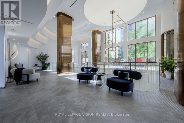 Bright, modern lobby with high ceilings, large windows, grey tiled floors, and plush seating areas. - 512 - 155 Merchants' Wharf, Toronto