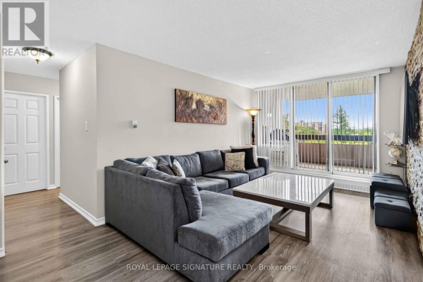 View of the living room from the entrance, showing the sectional sofa, coffee table, and balcony. - 512 - 1615 Bloor Street, Mississauga