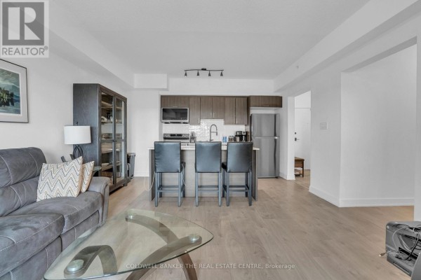 Close-up of kitchen area with dark wood cabinetry, modern appliances, and white backsplash. - 512 - 5 Chef Lane, Barrie
