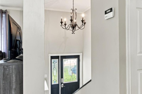 Interior view of a light grey entryway with a dark front door featuring stained glass windows. - 512 Main Road, St John S